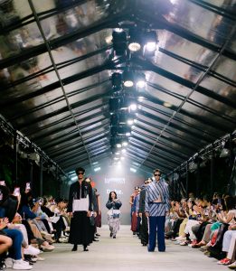Melalui NusaZen, Debz menghadirkan koleksi streetwear dengan siluet tailored yang diperkaya permainan asimetris berani. Material semi-wool bergaris, denim berkarakter tegas, katun ringan, dan batik berpadu menciptakan tampilan yang dinamis. Terinspirasi dari energi Harajuku, koleksi ini tampil urban dan ekspresif dengan palet warna hitam, putih, navy, serta sentuhan merah sebagai aksen modern yang kuat.